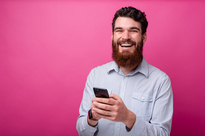 Lachender Mann mit Smartphone nutzt eine Dating App