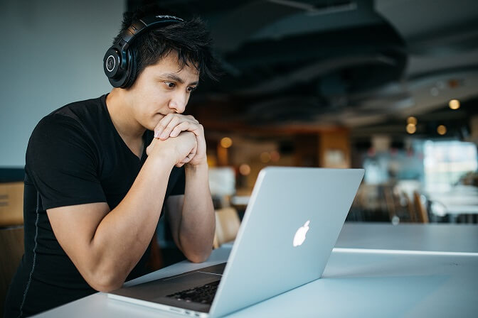 Asiatischer Single aktiv auf seinem Laptop mit Kopfhörern