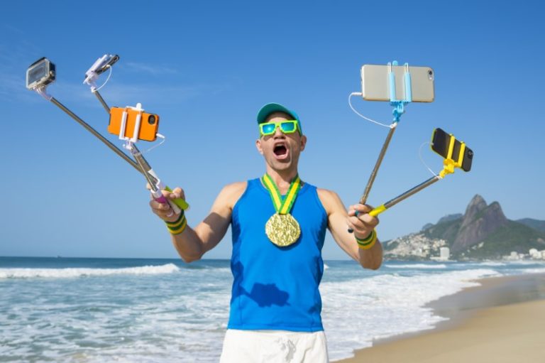 verrückter Kerl nimmt lustiges Selfie mit mehreren Selfie-Sticks am Strand auf