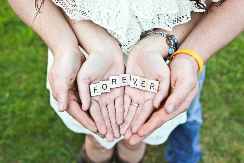 Paar, das gemeinsam die Worte "für immer" in den Händen hält.