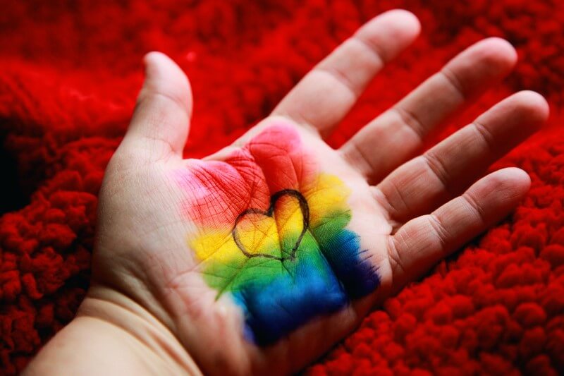 Handfläche mit LGBTQ+ Pride-Flagge und einem Herz
